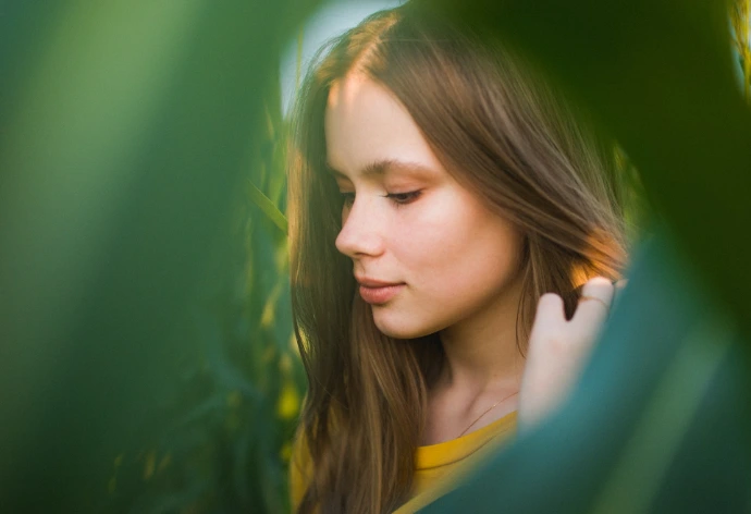 A young woman is looking down at her cell phone